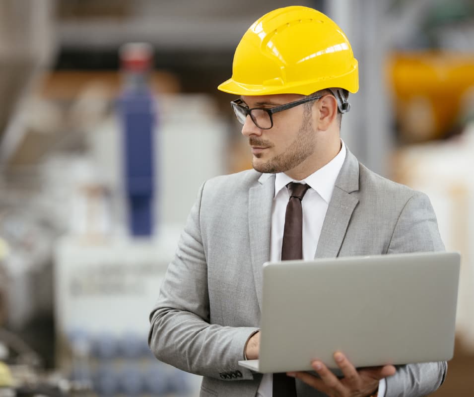 mezczyzna-z-laptopem-w-kasku-pilnujacy-bhp